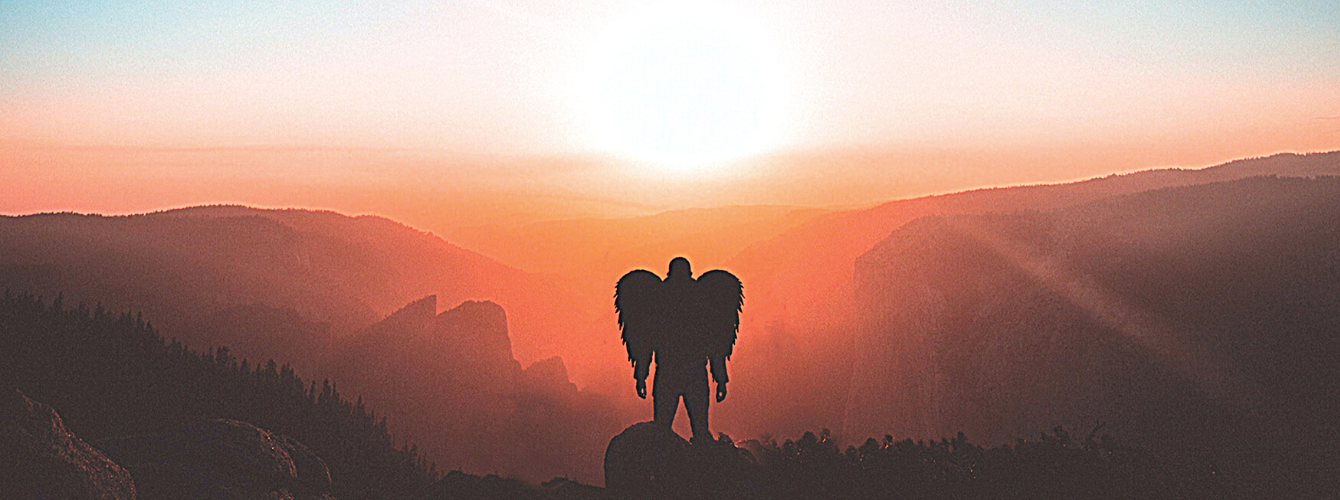 Angel figure standing in front of sunset